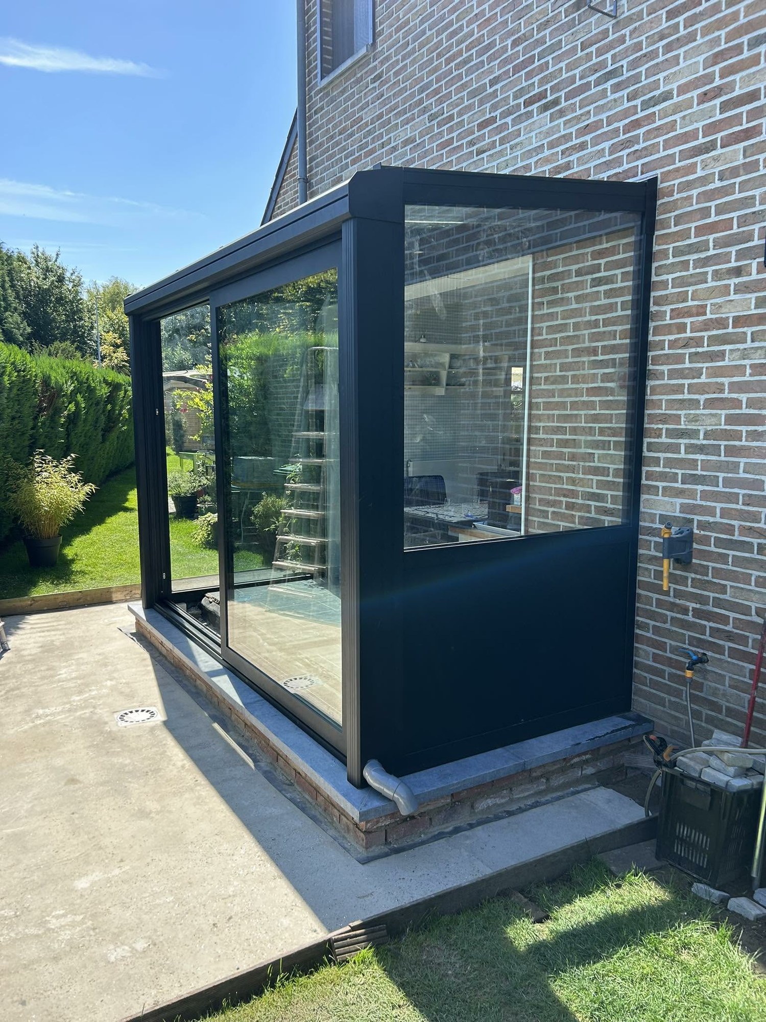 Petite véranda anthracite vitrée en fond de jardin