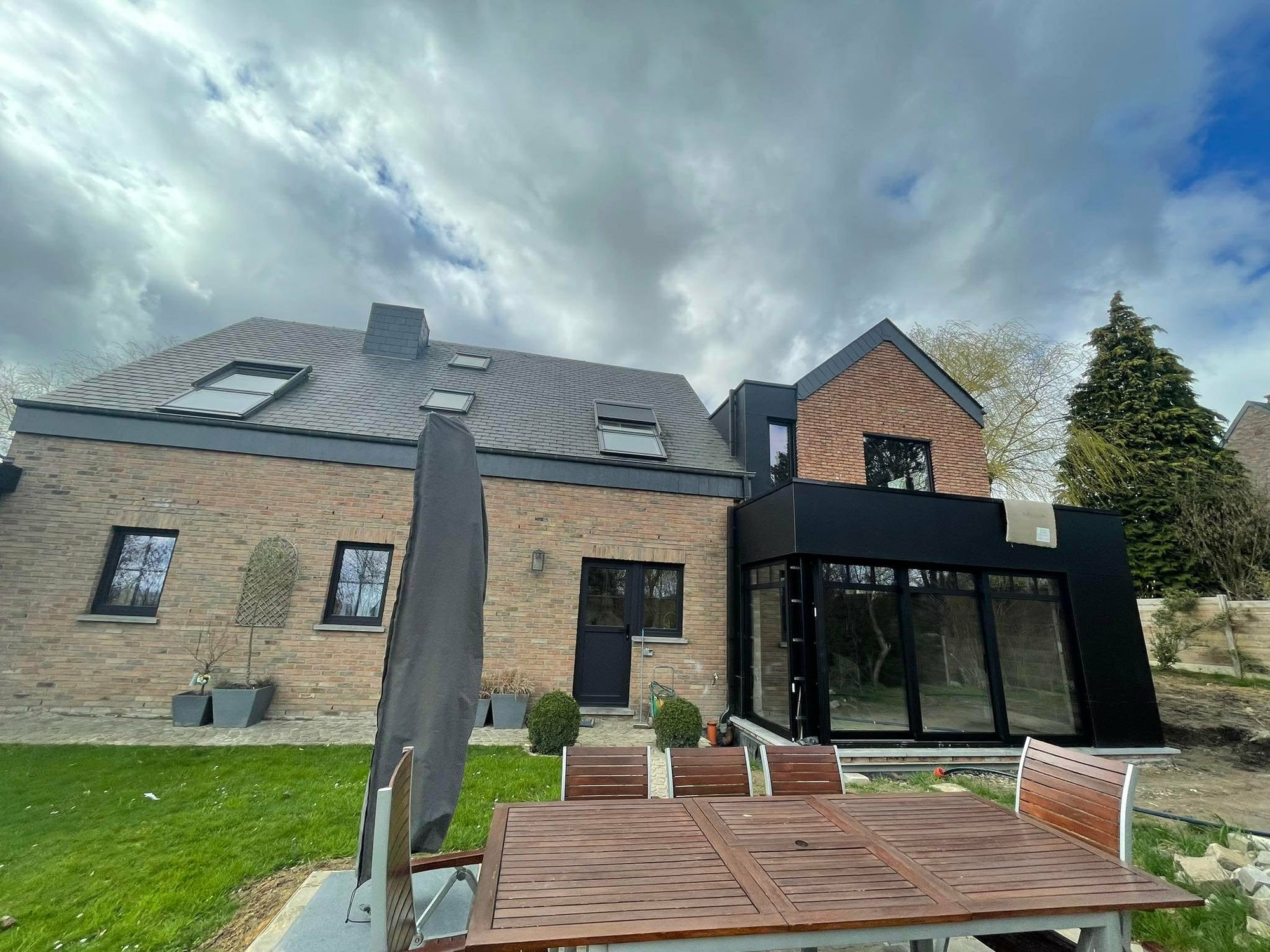 Maison avec extension noire vitrée ouverte sur le jardin