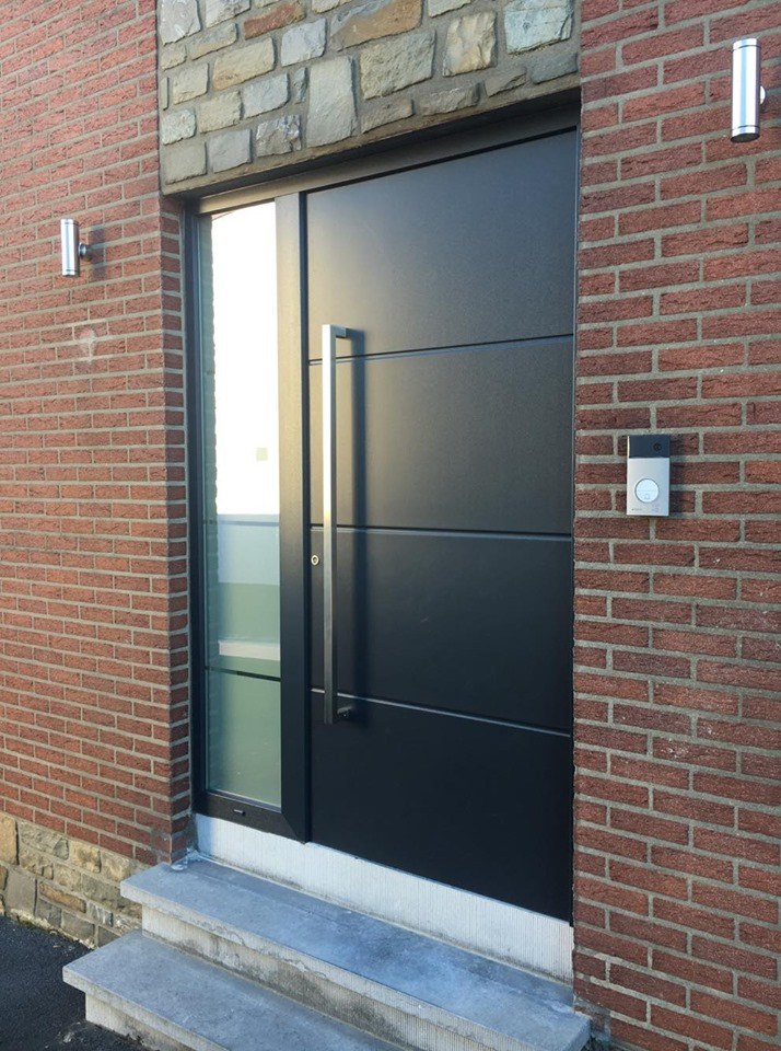 Porte d'entrée aluminium anthracite à poignée barre dans une façade en brique
