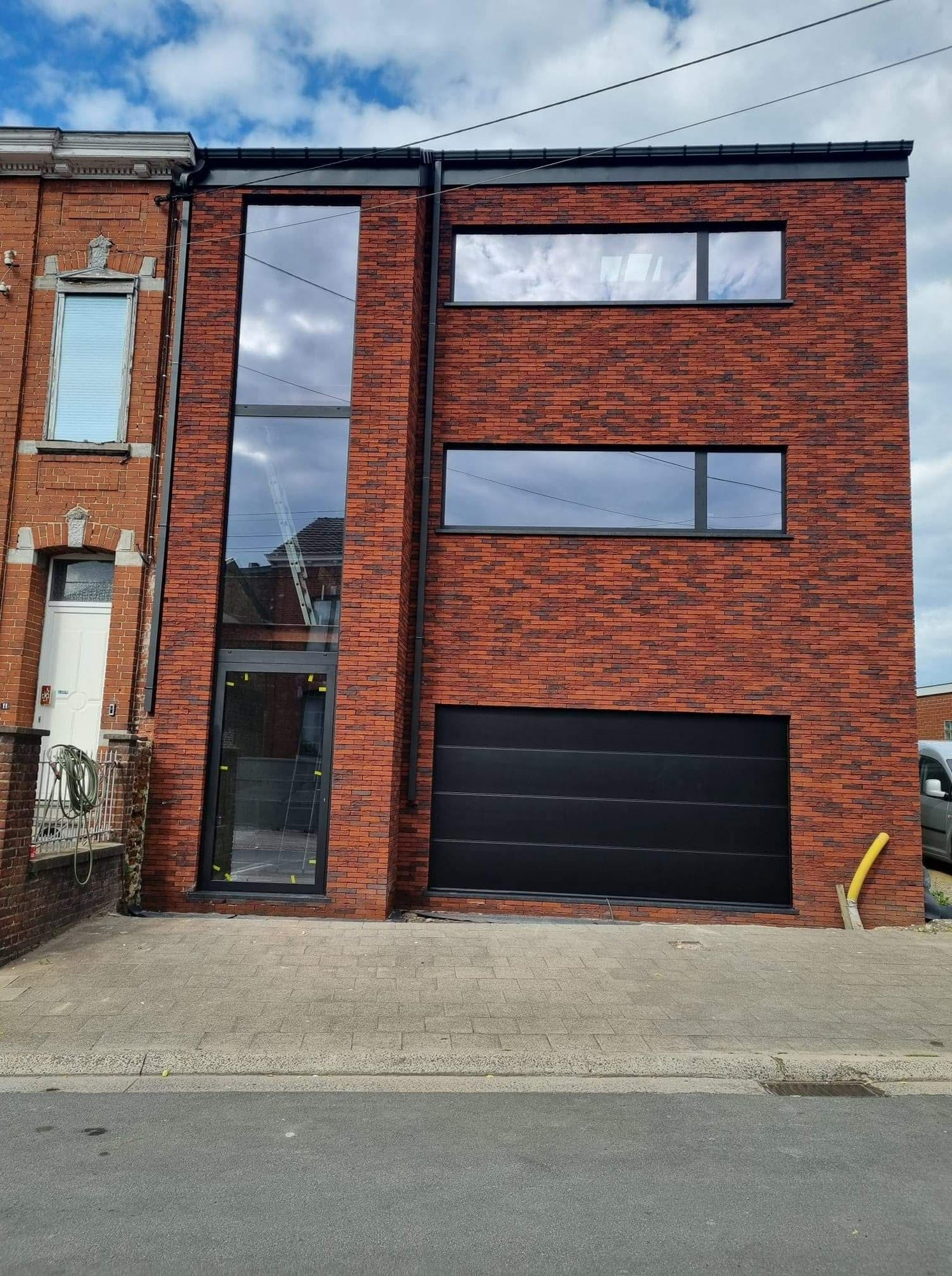 Façade en brique rouge avec bandeaux vitrés et porte de garage sectionnelle